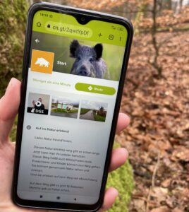 Hand hält Smartphone mit App der Wildschweinroute