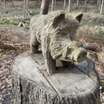Aus Holz geschnitztes Wildschwein auf einem Baumstumpf