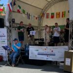 Eine inklusive Band spielt auf einer Bühne mit internationalen Flaggen im Hintergrund bei einer Veranstaltung von oberursel all inclusive