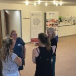 Vier Frauen stehen an der Eingangstür zum Veranstaltungsraum vor zwei aufgestellten Roll-ups