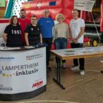 Sechs Mitarbeitende der Lebenshilfe Lampertheim stehen hinter einem Infotisch mit Flyern und Plakaten