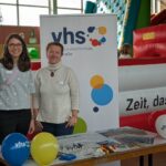 Zwei Mitarbeiterinnen der Vhs Bergstraße an ihrem Infotisch mit Luftballons und Flyern